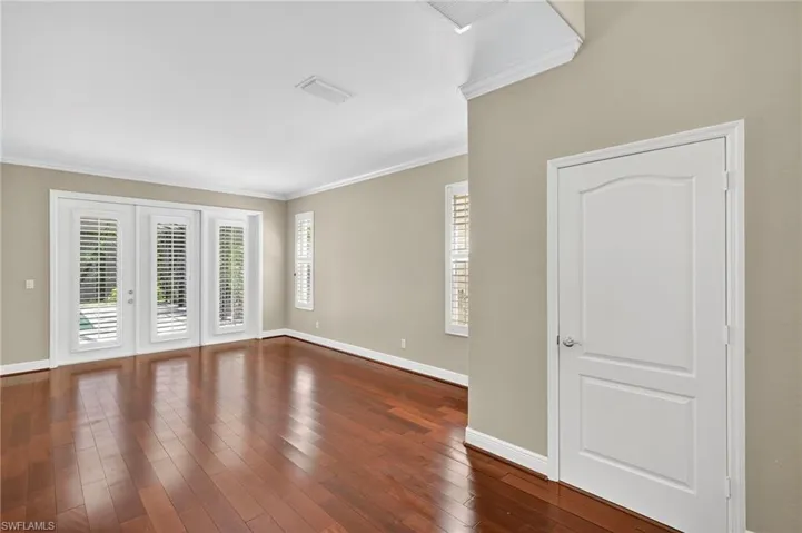 Empty room featuring ornamental molding, dark wood finished floors, and french doors