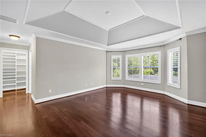 Empty room with ornamental molding and dark wood-type flooring