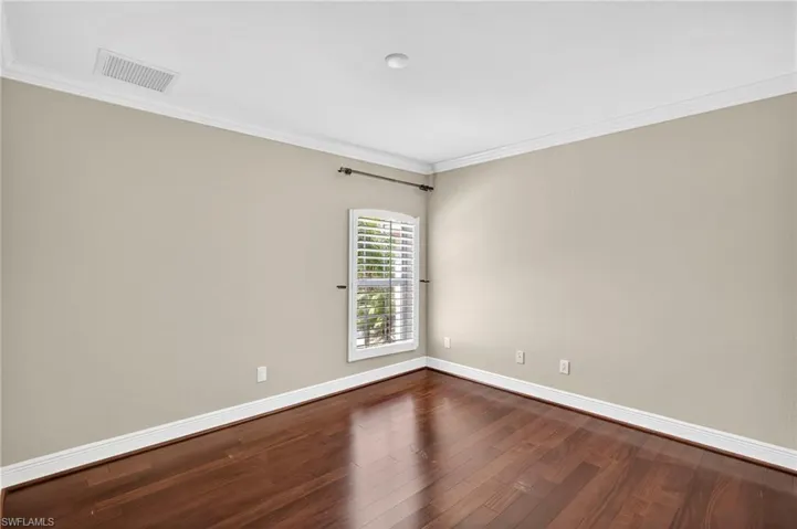 Spare room featuring crown molding and dark wood-type flooring