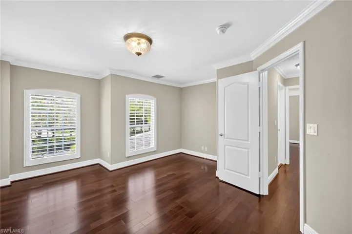 Unfurnished room featuring ornamental molding and dark wood-style floors