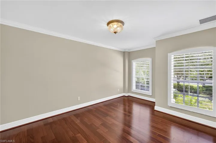 Unfurnished room with ornamental molding and dark wood-style flooring