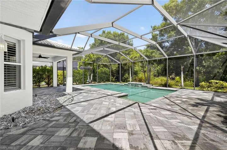 Outdoor pool featuring glass enclosure, a patio area, a sunroom, and ceiling fan