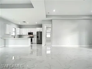 Kitchen with light tile patterned flooring, stainless steel appliances, and white cabinets