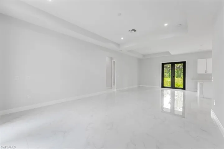 Spare room featuring beamed ceiling, french doors, a tray ceiling, and light tile patterned floors