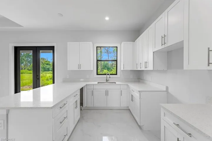 Kitchen with light tile patterned flooring, light stone countertops, and a wealth of natural light