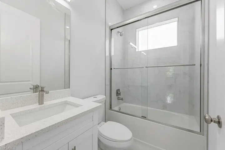 Full bathroom with vanity, toilet, and enclosed tub / shower combo