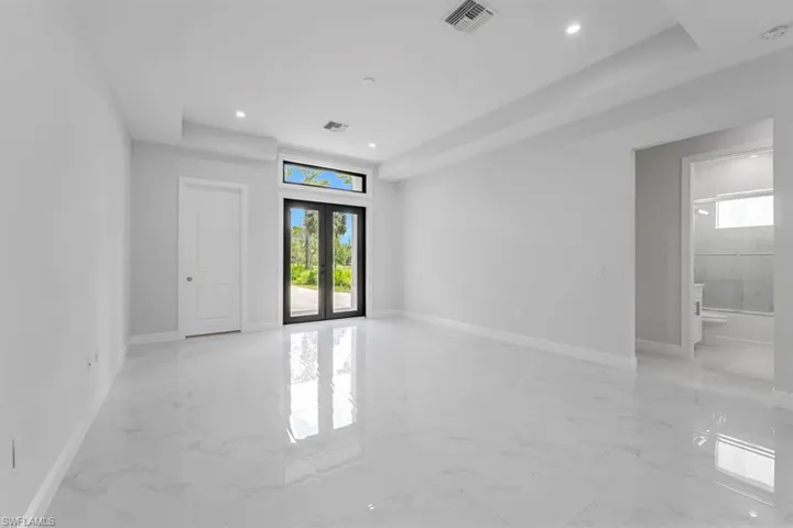 Spare room featuring a raised ceiling, light tile patterned floors, and french doors