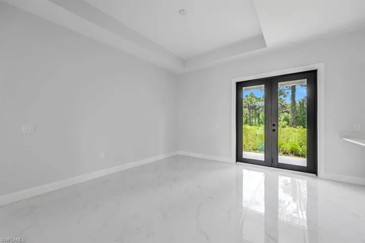 Tiled empty room featuring french doors and a raised ceiling