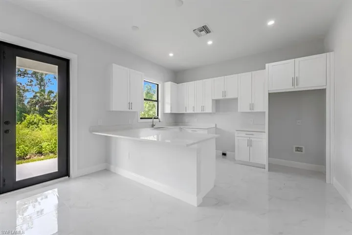 Kitchen with white cabinetry, sink, light tile patterned floors, and kitchen peninsula