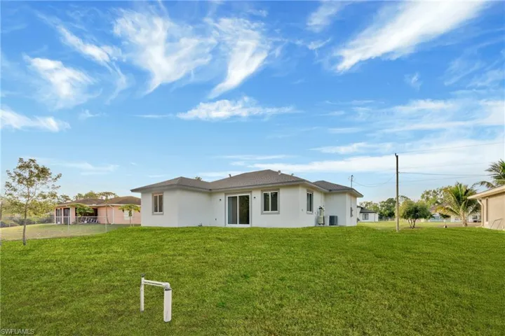 Rear view of property with stucco siding and a yard