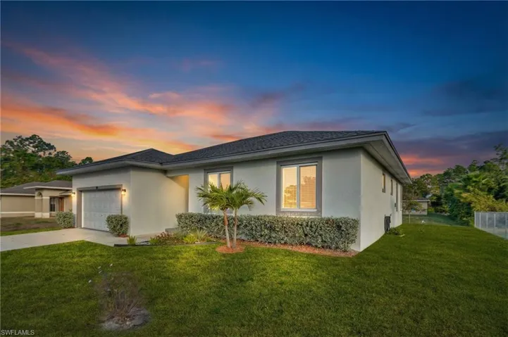 View of front of home featuring a lawn, stucco siding, and a garage