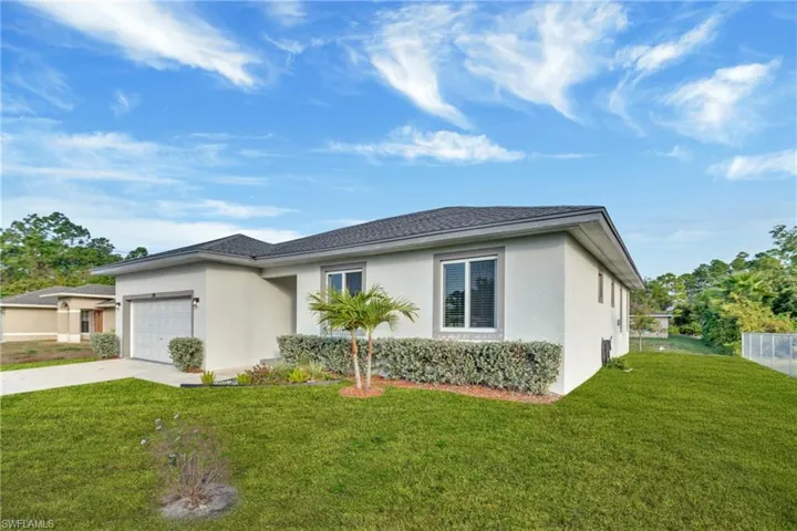 View of front of home with stucco siding, a front yard, and concrete driveway