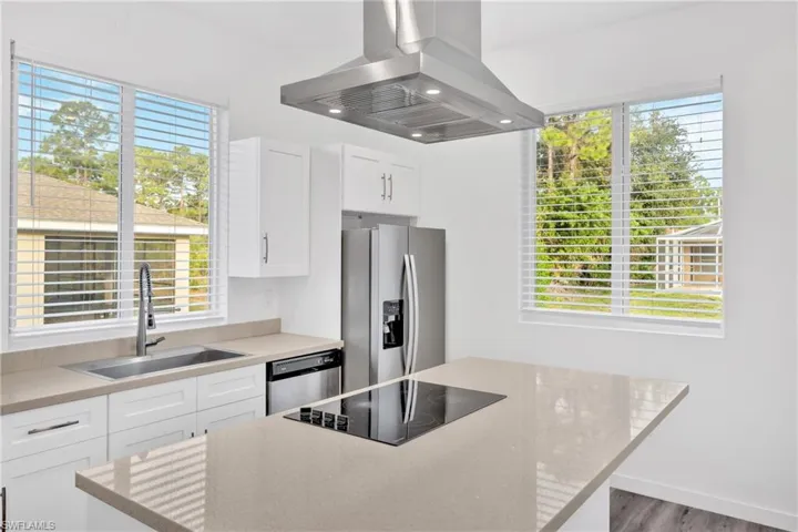 Kitchen featuring island range hood, light stone counters, white cabinets, appliances with stainless steel finishes, and recessed lighting