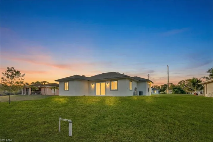 Rear view of house featuring stucco siding and a lawn