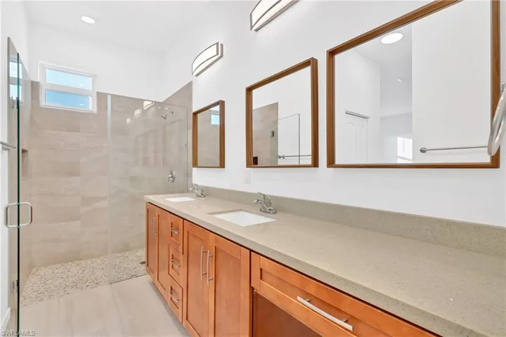 Bathroom with a shower stall, double vanity, and recessed lighting