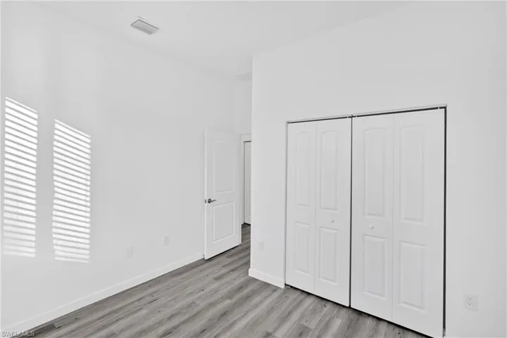 Unfurnished bedroom featuring a closet, light wood-style floors, and a towering ceiling