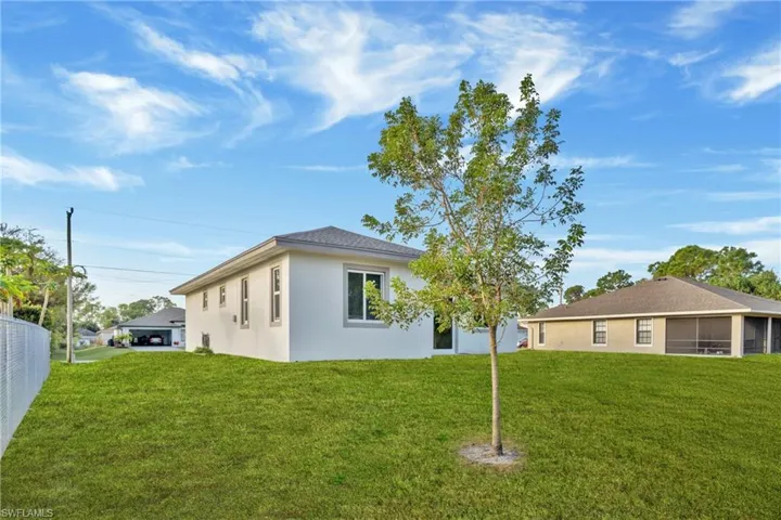 Rear view of house featuring a lawn, a sunroom, and stucco siding