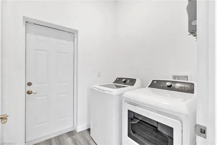 Laundry area with washing machine and clothes dryer and light wood-style flooring