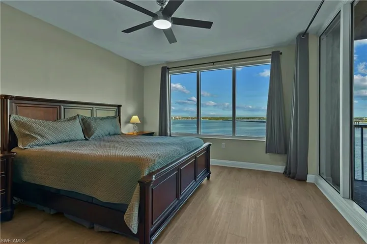 Bedroom featuring ceiling fan, light hardwood / wood-style floors, and a water view