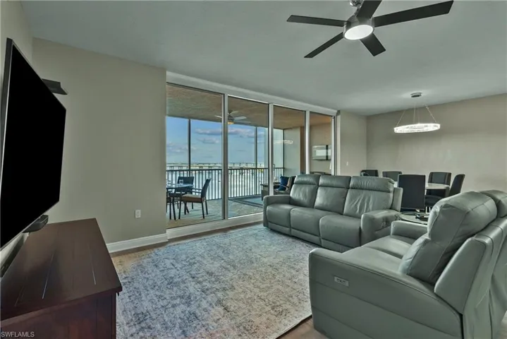 Living room with hardwood / wood-style flooring, ceiling fan, expansive windows, and a water view
