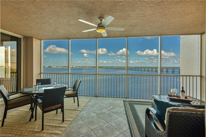 Sunroom / solarium featuring ceiling fan and a water view