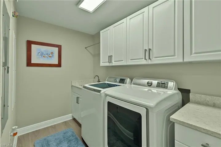 Laundry room with cabinets, separate washer and dryer, sink, and light hardwood / wood-style flooring