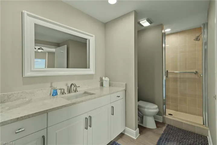 Bathroom with toilet, vanity, a shower with shower door, and hardwood / wood-style flooring