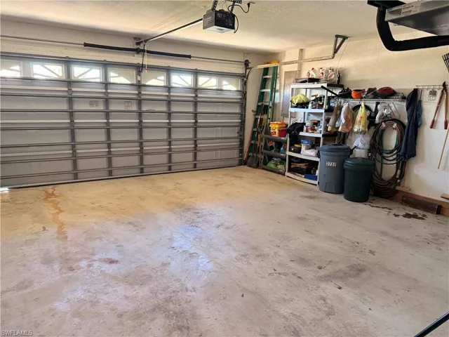 Garage with a garage door opener, a textured wall, and a heating unit