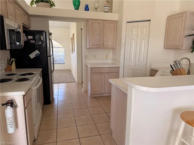 Kitchen featuring stainless steel appliances, light wood finish cabinetry, light countertops, and light tile patterned floors