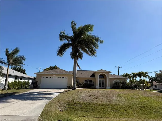 Single story home featuring a front yard, driveway, a garage, and french doors