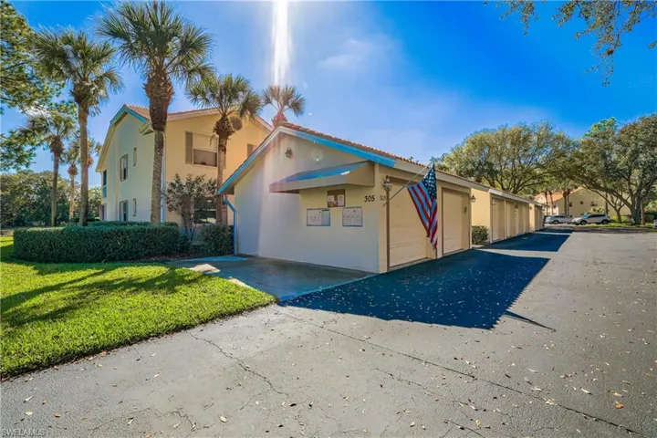 View of front of property featuring stucco siding, community garages, and a front yard