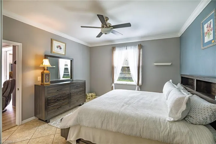 Bedroom with crown molding, light tile patterned floors, and ceiling fan