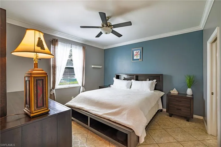 Bedroom with ornamental molding, a ceiling fan, and tile patterned floors