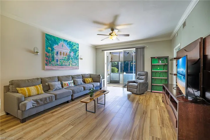 Living room with ornamental molding, a ceiling fan, and light wood-style floors