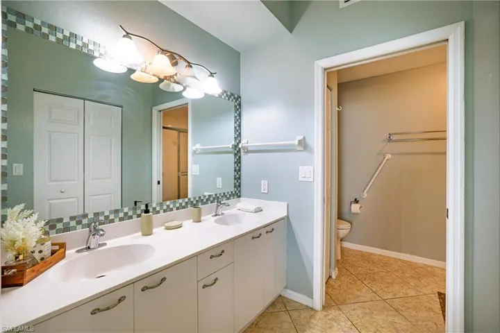 Bathroom featuring double vanity, a closet, and light tile patterned floors