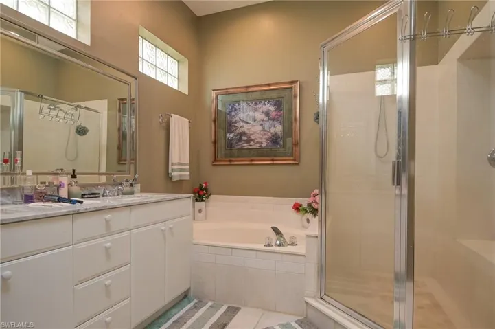 Full bathroom featuring double vanity, a bath, a stall shower, and light tile patterned floors