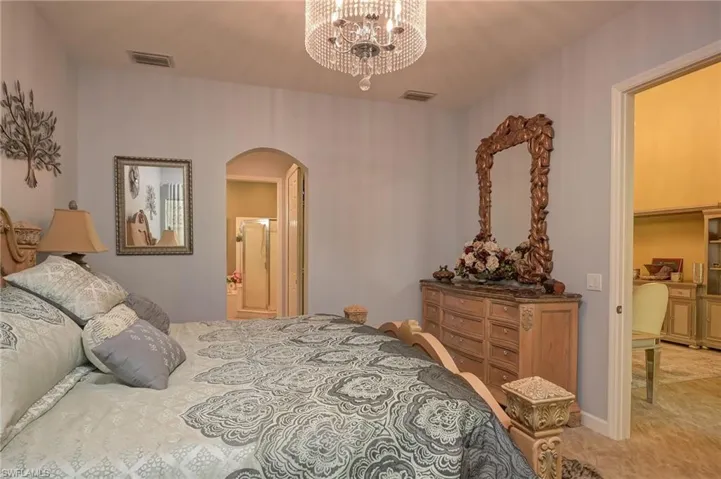 Bedroom with arched walkways, a chandelier, and ensuite bath