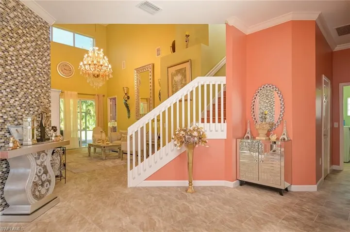 Stairs featuring ornamental molding, a chandelier, and a towering ceiling