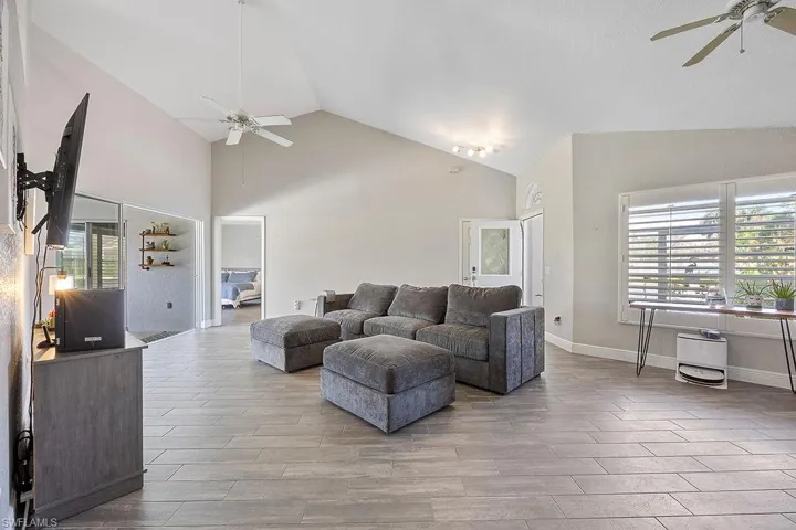 Living room featuring high vaulted ceiling, light wood-type flooring, and ceiling fan