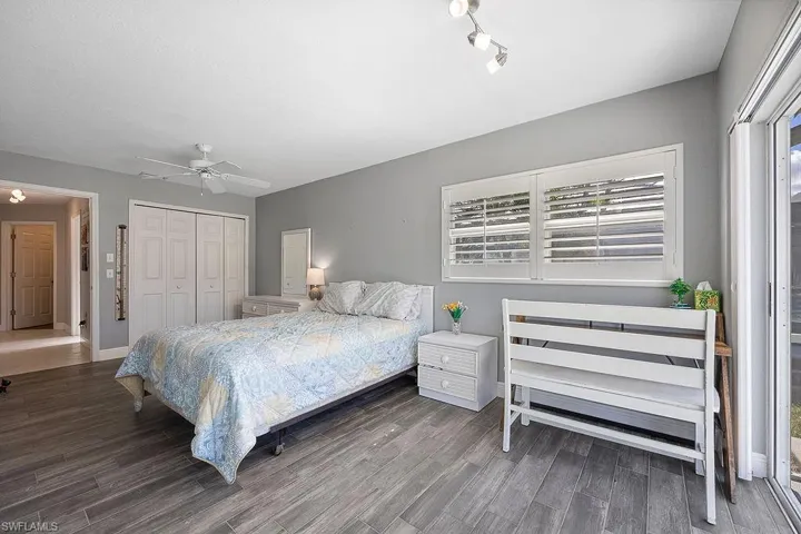 Bedroom with ceiling fan, dark hardwood / wood-style floors, and a closet