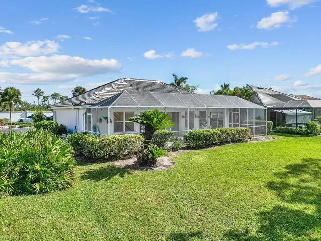 Rear view of property with a lawn and a lanai