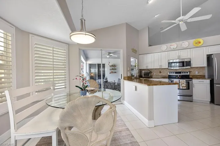 Kitchen featuring dark stone counters, high vaulted ceiling, white cabinetry, and appliances with stainless steel finishes