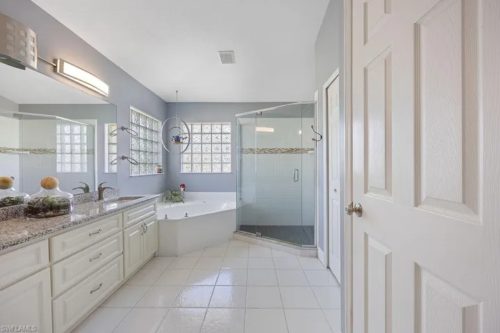 Bathroom featuring vanity, plus walk in shower, an inviting chandelier, and tile patterned flooring