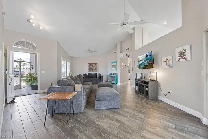 Living room with hardwood / wood-style flooring, ceiling fan, and high vaulted ceiling