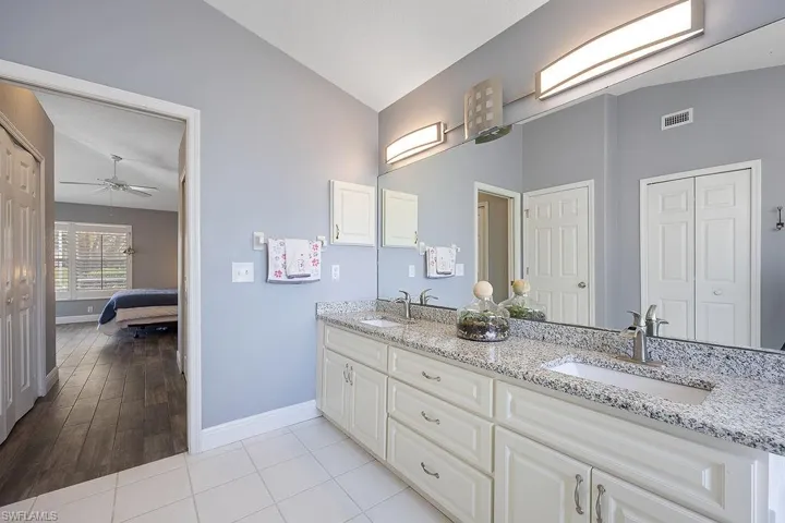 Bathroom with ceiling fan, wood-type flooring, vanity, and vaulted ceiling