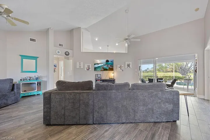 Living room featuring high vaulted ceiling, wood-type flooring, and ceiling fan