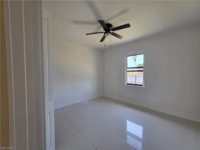 Empty room featuring light tile patterned flooring and a ceiling fan