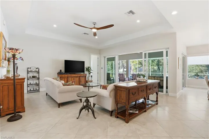 Living area featuring a ceiling fan, a raised ceiling, recessed lighting, and light tile patterned floors