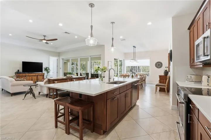Kitchen with a breakfast bar area, hanging light fixtures, open floor plan, stainless steel appliances, and a large island with sink