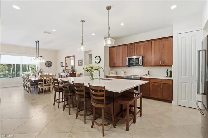 Kitchen with pendant lighting, a kitchen island with sink, a kitchen breakfast bar, recessed lighting, and appliances with stainless steel finishes